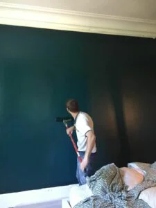 homme passant un rouleau de peinture sur un mur